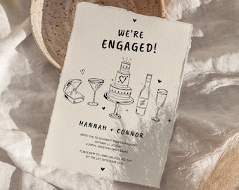 Puede incluir: Una tarjeta de anuncio de compromiso en blanco y negro con ilustraciones de un anillo, una copa de martini, un pastel, una botella de vino y una copa de champán. El texto dice "We're Engaged!" e incluye los nombres de la pareja, Hannah y Connor, la fecha y la hora de su fiesta de compromiso, y la información de RSVP.