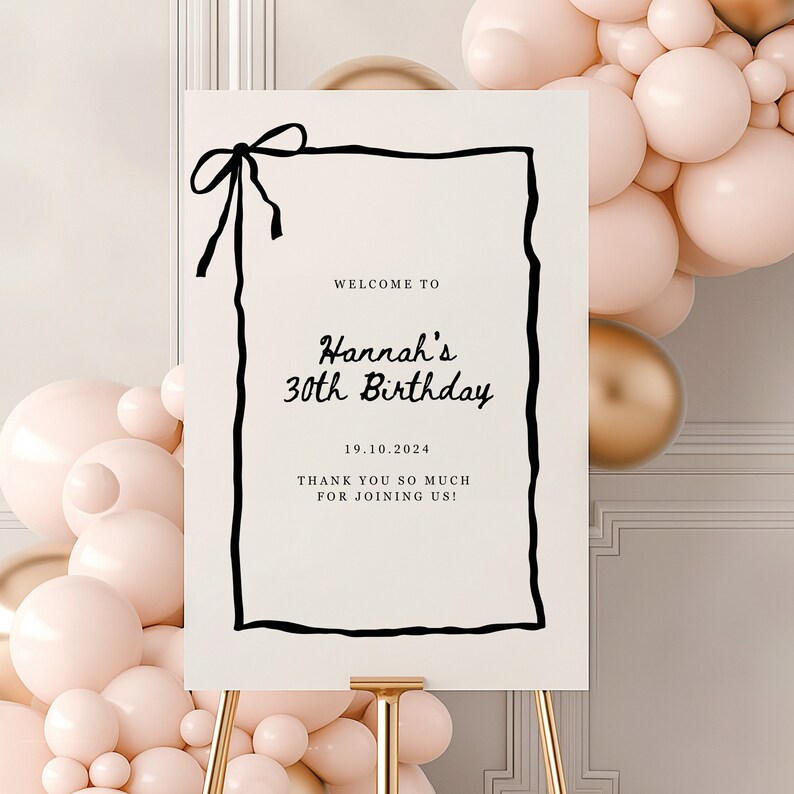 K&ouml;nnte beinhalten: Ein wei&szlig;es Willkommens-Schild mit einem schwarzen handgezeichneten Rahmen und einer schwarzen Schleife oben. Das Schild sagt "Willkommen zu Hannah's 30th Birthday 19.10.2024 Vielen Dank, dass Sie mit uns feiern!"