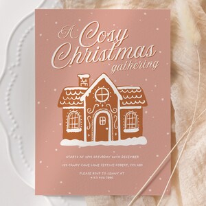 May include: A pink invitation card with the text "A Cosy Christmas gathering". It features a gingerbread house illustration in brown with white accents. The card includes event details and a phone number.