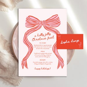 May include: A festive Christmas menu card with a pink and red bow design. The text reads "a holly jolly Christmas feast" with menu items listed below. A matching red name card is also present.