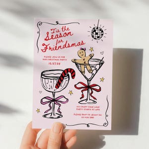 May include: Pink Christmas party invitation with a hand-drawn illustration of two martini glasses. One glass has a gingerbread man inside and the other has a candy cane. The text reads "Tis the Season for Friendsmas" and includes the date "12.27.25", the address "123 Candy Cane Lane", and the time "Party starts at 5PM".