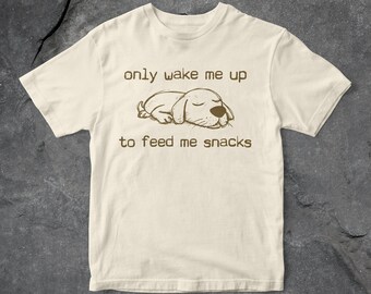 May include: A beige t-shirt with a brown cartoon dog sleeping and the text "only wake me up to feed me snacks".