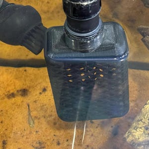 May include: A black aquarium filter with a grid pattern on the front. The filter is submerged in water and is attached to a black hose.