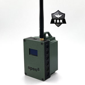 May include: A green, rectangular device with a black antenna, a small screen, and the text "spec5" on the front. The device has a black hexagonal pattern on the side.