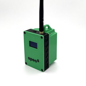 May include: A green and black electronic device with a black antenna and a small screen. The device has the text "spec5" printed on the front.