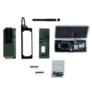 May include: A kit for building a green and black radio transmitter with a circuit board, antenna, case, and other components. The kit includes a small bag of screws, two sets of pin headers, and a green circuit board with the text "spec05" and "RST, IO38, PWR".