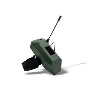 May include: A green, angular device with a black antenna and a small screen. It is attached to a black wrist strap. The device has a textured surface and appears to be made of plastic.