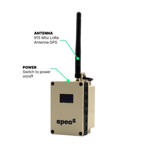 May include: A beige and black spec5 device with a black antenna, a power switch, and a small screen. The text "spec5" is printed on the front of the device.