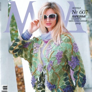 May include: A magazine cover featuring a woman wearing a crocheted jacket with floral designs in shades of green, purple, and yellow. The magazine is titled "ВЯЗАНИЕ" and the text "крючок спицы" is also visible. The magazine cover also includes the text "журнал № 607 НАРЯДНЫЕ ШЕДЕВРЫ идеи и изысканный декор".