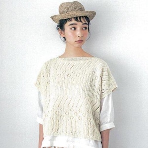 Puede incluir: Una mujer con un sombrero de paja y un top de punto color crema con un patrón de diamantes. El top se combina con una camisa blanca y una falda a rayas. El texto "COTTON AND LINEN KNIT" es visible en la parte superior de la imagen.