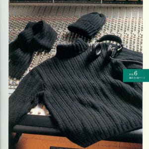 May include: A black turtleneck sweater, a black knit hat, and a pair of headphones are laid out on a soundboard. The text "作品 6 編み方/60ページ" is visible in the lower right corner of the image.