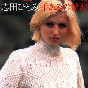 Op de afbeelding: Een vrouw met blond haar staat op de omslag van een Japans breiboek. De titel van het boek staat in Japanse karakters, met de woorden "Let's knit series" in het Engels. Ze draagt een witte, ingewikkeld gebreide coltrui.