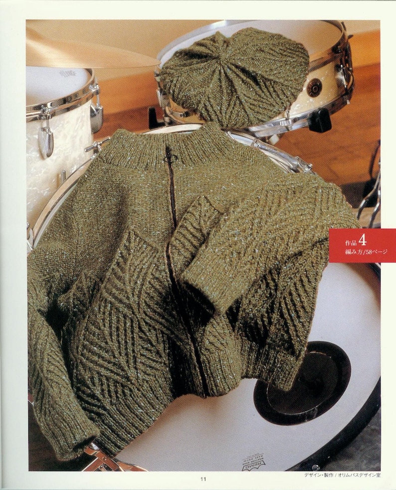 May include: A green knitted cardigan with a zipper closure and a diamond pattern. The cardigan is laid out on a drum.