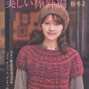May include: A book cover from the "Let's Knit Series" features a woman wearing a knitted red and purple sweater and a brown fur hat. The Japanese text includes "Beautiful Knitting" and "Autumn 2". The book cover also mentions vests, tunics, and ponchos.