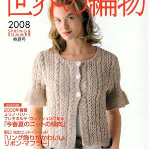 May include: A magazine cover featuring a woman wearing a beige knitted cardigan with a cable knit pattern. The magazine is titled "World Knitting" and the cover text says "Spring & Summer 2008".