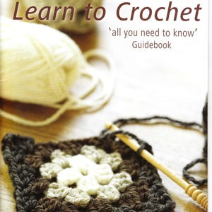 Könnte beinhalten: Ein Buch mit dem Titel "Learn to Crochet" mit einem Häkelprojekt und Garn im Hintergrund. Das Buchcover zeigt das Patons-Logo und den Text "all you need to know' Guidebook". Das Bild enthält auch den Text "CONTAINS 20 EASY PROJECTS FROM ACCESSORIES TO HOMEWARES, FOR THOSE NEW TO CROCHET."