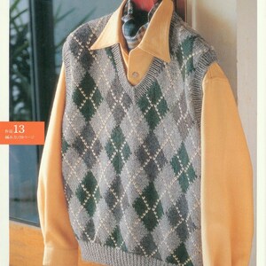 May include: A gray and green argyle knit vest with a V-neck. The vest is hanging on a hanger and is being worn over a yellow button-down shirt.
