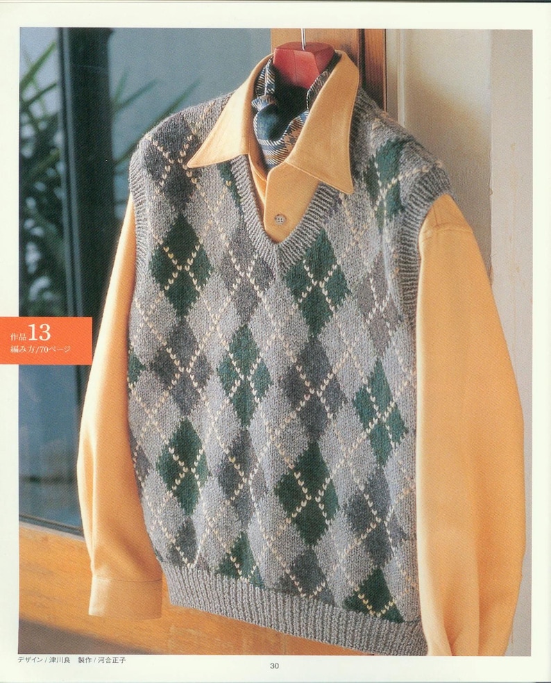 May include: A gray and green argyle knit vest with a V-neck. The vest is hanging on a hanger and is being worn over a yellow button-down shirt.