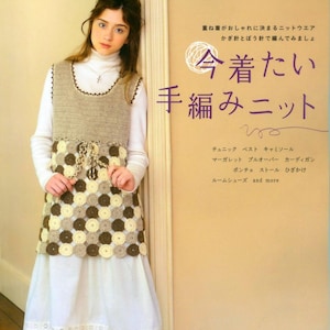 Könnte beinhalten: Ein Buchcover mit einer jungen Frau, die eine gehäkelte Weste und einen Rock trägt. Der Buchtitel lautet "Jetzt möchte ich stricken" auf Japanisch. Das Cover zeigt auch eine Vielzahl von gehäkelten Artikeln, darunter eine Weste, einen Rock, einen Schal und eine Mütze.