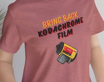 May include: A heather red t-shirt with the text "Bring Back Kodachrome Film" in yellow and orange lettering. A yellow and red film canister with the text "400" is pictured below the text.