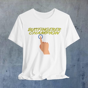 May include: White t-shirt with the text "Buttfingerer Champion" in yellow letters and a cartoon hand pointing at a blue circle.