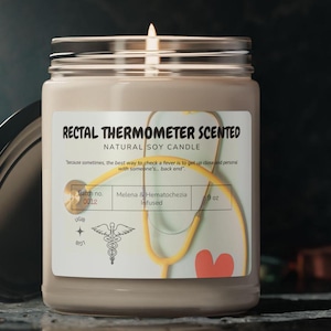 Puede incluir: Una vela de vidrio marrón en un frasco con una etiqueta blanca que dice "Rectal Thermometer Scented Natural Soy Candle". La etiqueta también incluye un estetoscopio, un corazón y el texto "Batch no. 0012 Melena & Hematochezia Infused 9 oz".