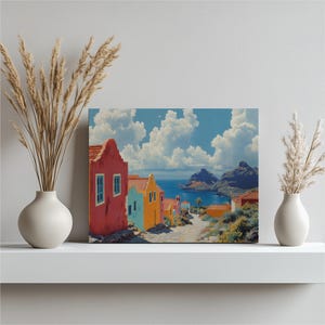 Puede incluir: Una pintura colorida representa un pueblo costero con edificios rojos, azules y amarillos. La obra de arte muestra un camino que conduce al mar bajo un cielo azul brillante con nubes blancas. La pintura se exhibe en una estantería blanca.