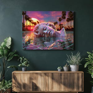 Puede incluir: Impresión en lienzo que muestra una escultura de un rostro sumergido en agua. La obra presenta una puesta de sol con palmeras al fondo. El agua refleja los colores del atardecer, creando una escena vibrante y surrealista. La temática es arte y naturaleza.