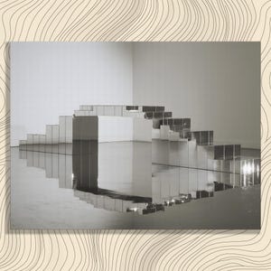 May include: A reflective, silver-toned sculpture composed of numerous rectangular blocks arranged in a stepped, bridge-like formation. The metallic surface creates a clear mirror effect, reflecting the surrounding space and creating a symmetrical visual.