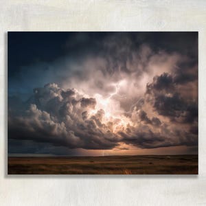 May include: A dramatic landscape photograph of a thunderstorm. Dark, billowing storm clouds dominate the sky, with flashes of lightning illuminating the scene. The foreground features a field of dry grass under a darkening sky.