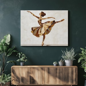 May include: A framed artwork depicts a ballerina in a graceful pose. The dancer's form is constructed from various shades of brown and tan geometric shapes, creating a mosaic effect. The background is a light, off-white color, and the artwork is displayed on a dark green wall.