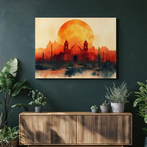 May include: A canvas print depicting a desert landscape with a church silhouetted against a large orange sun. The artwork features cacti and mountains in shades of red, orange, and brown, creating a warm, atmospheric scene.