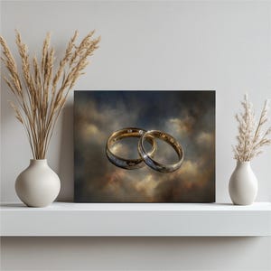 May include: A canvas print featuring two gold wedding rings, one with a small diamond, set against a cloudy, atmospheric background. The rings are the focal point, symbolizing commitment and love.