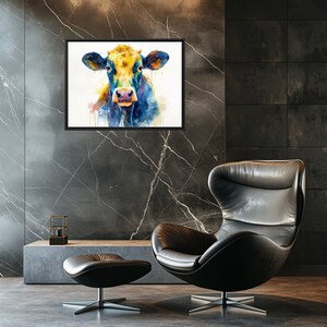 Może przedstawiać: Oprawiony akwarelowy obraz przedstawiający pysk krowy, z żółtymi, niebieskimi i pomarańczowymi odcieniami. Dzieło sztuki jest wystawione na ciemnej marmurowej ścianie nad czarnym skórzanym fotelem i pufą. Pokój ma nowoczesny, minimalistyczny design.