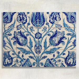 Op de afbeelding: Een set van twaalf keramische tegels gerangschikt in een rechthoekig patroon. Elke tegel heeft een gedetailleerd bloemmotief in blauwtinten tegen een crèmekleurige achtergrond. Het patroon bevat gestileerde bloemen, bladeren en wijnranken, wat een samenhangend decoratief element creëert.