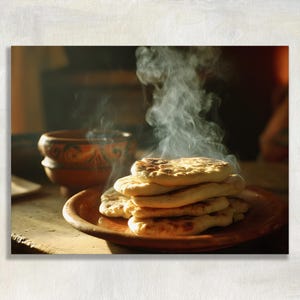 May include: A stack of freshly baked, steaming flatbreads rests on a round, rustic terracotta plate. The golden-brown bread features charred spots from the cooking process. A matching terracotta bowl with decorative patterns sits nearby.