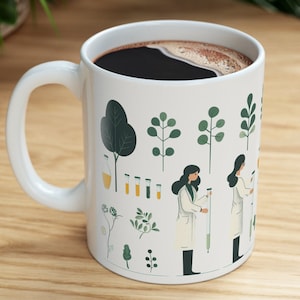 Könnte beinhalten: Weißer Keramikbecher gefüllt mit dunklem Kaffee. Der Becher hat ein botanisches und wissenschaftliches Design mit Illustrationen von Pflanzen, Laborgeräten und Wissenschaftlerinnen in Laborkitteln. Der Griff ist weiß.