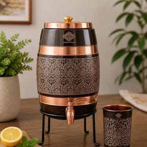 May include: A barrel-shaped water dispenser with a black and copper finish, featuring an intricate floral pattern, a copper-colored spigot, and a matching cup. The dispenser sits on a black metal stand and includes a lid with a gold-toned knob.