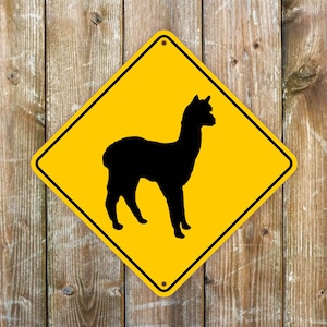 May include: Yellow diamond-shaped road sign with a black silhouette of an alpaca. The sign has a black border and the text "Caution" is printed in black at the top.