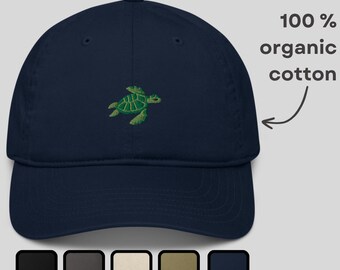 May include: A navy blue baseball cap with a green embroidered turtle design. The cap is made of 100% organic cotton. The image also shows a selection of color options for the cap.
