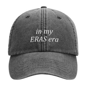 May include: A black denim baseball cap with white embroidered text that reads "in my ERAS era".