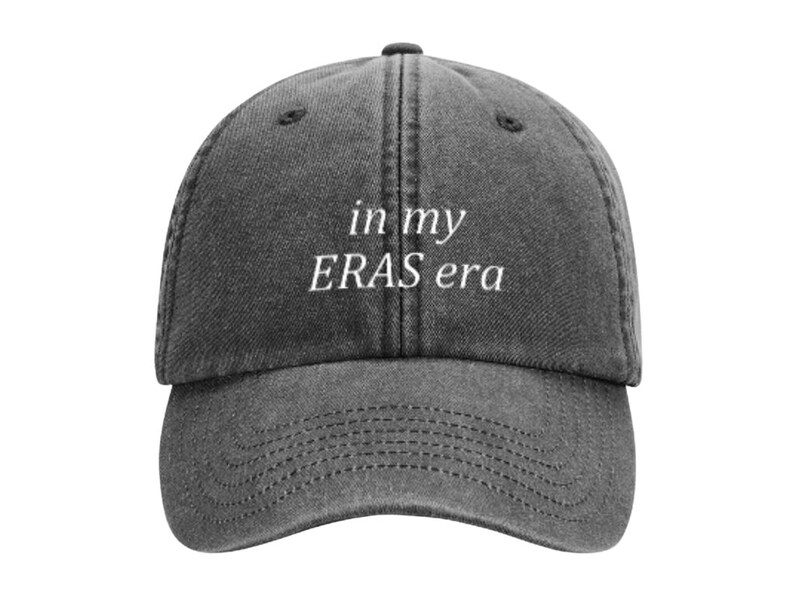 May include: A black denim baseball cap with white embroidered text that reads "in my ERAS era".