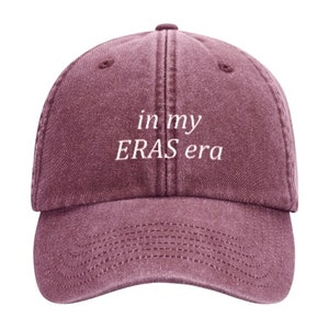 May include: A maroon baseball cap with the text "in my ERAS era" embroidered in white on the front.