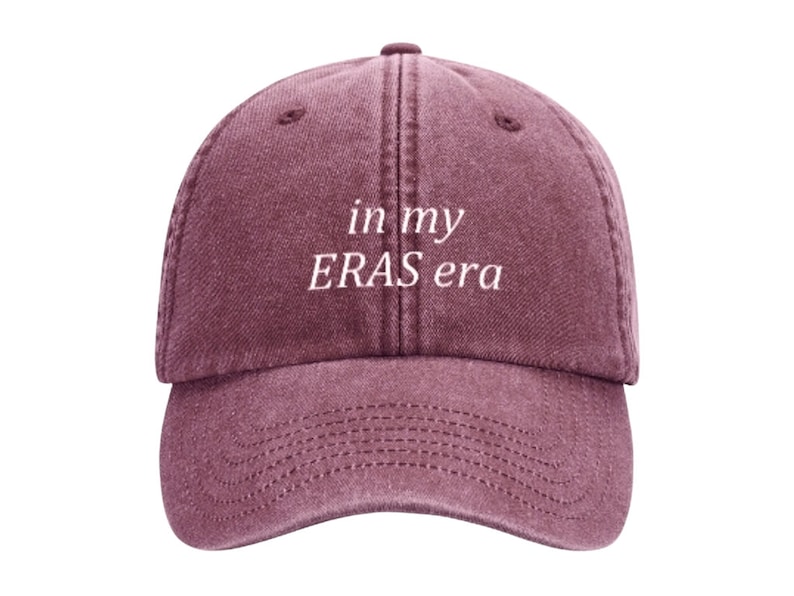 May include: A maroon baseball cap with the text "in my ERAS era" embroidered in white on the front.