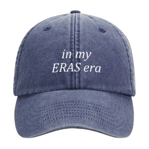 May include: A blue denim baseball cap with white embroidered text that reads "in my ERAS era".