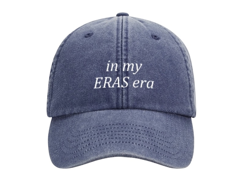 May include: A blue denim baseball cap with white embroidered text that reads "in my ERAS era".