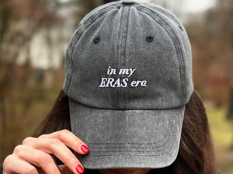 May include: A gray baseball cap with the text "in my ERAS era" embroidered in white on the front.