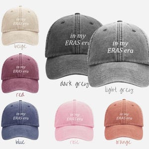 May include: A set of ten baseball caps in various colors, each featuring the text "in my ERAS era" embroidered on the front. The caps are made of a soft, distressed denim fabric.