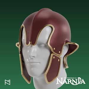Könnte beinhalten: Ein weinroter Helm mit goldenen Verzierungen, der ein markantes Design mit Ohrenklappen und dekorativen Elementen aufweist. Der Helm wird auf einem weißen Schaufensterkopf präsentiert. Das Logo Die Chroniken von Narnia ist sichtbar.