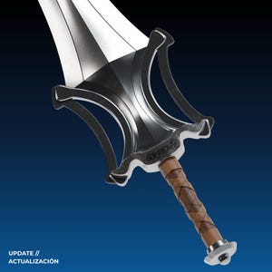 Peut inclure: Une &eacute;p&eacute;e argent&eacute;e et noire avec une poign&eacute;e envelopp&eacute;e de cuir. La lame est polie et la garde a un design d&eacute;coratif. L'&eacute;p&eacute;e est pos&eacute;e sur un fond bleu fonc&eacute;. Le texte en bas indique "UPDATE // ACTUALIZACI&Oacute;N."